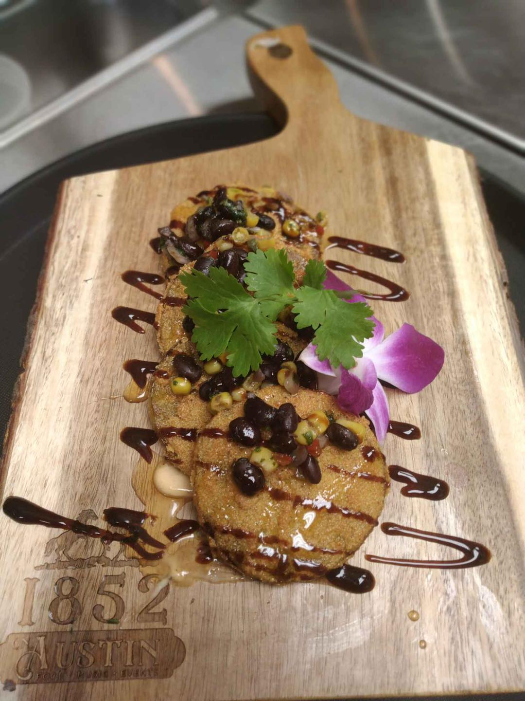 appetizer drizzled with balsamic vinagrette on a 1852 on Austin cutting board